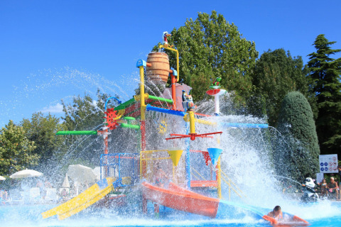 Zona acuática en Camping Bella Italia, Véneto, Italia, con toboganes coloridos y chorros de agua refrescantes.