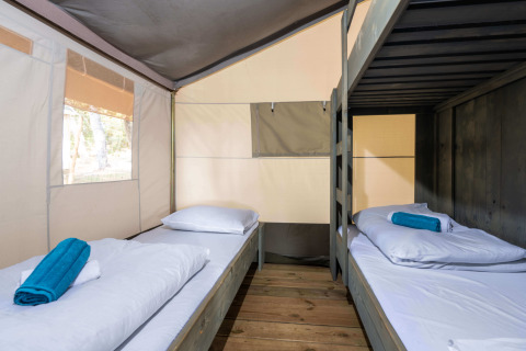 Interior de una Safari Tent Luxury con literas y suelo de madera en Koversada Camping Resort en Croacia.