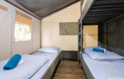Binnenkant van Safari Tent Luxury met stapelbedden en houten vloer op Koversada Camping Resort in Kroatië.