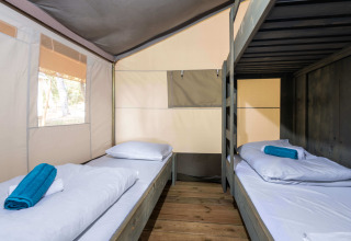 Interno di Safari Tent Luxury con letti a castello e pavimento in legno al Koversada Camping Resort in Croazia.