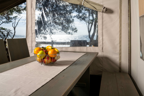 Vista interior de la Safari Tent Luxury en Koversada Camping Resort con bol de frutas y vista al mar.