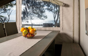 Vista interior de la Safari Tent Luxury en Koversada Camping Resort con bol de frutas y vista al mar.