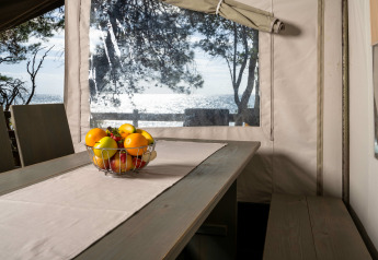 Vista interna della Safari Tent Luxury al Koversada Camping Resort con cesta di frutta e vista mare.