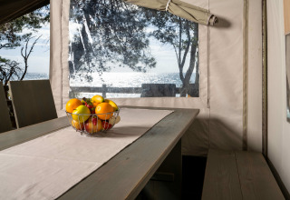 Interior view of Safari Tent Luxury at Koversada Camping Resort with a fruit bowl and sea in background.