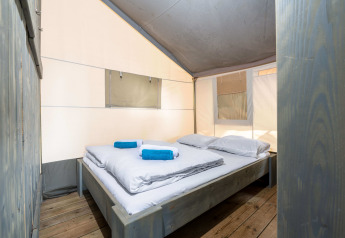 Vista interior de la Safari Tent Luxury en Koversada Camping Resort, Croacia, con cama doble y toallas azules.