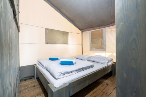 Vista interna della Safari Tent Luxury al Koversada Camping Resort in Croazia, con letto matrimoniale e asciugamani.