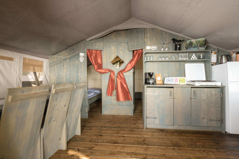 Interno della Safari Tent Luxury al Koversada Camping Resort in Croazia con angolo cucina e camera.