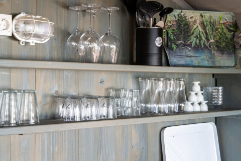 Estantes de cocina con vasos y utensilios en una tienda safari de lujo con tabla de hierbas decorativa.