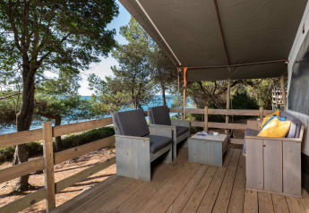 Houten veranda met comfortabele stoelen en uitzicht op zee bij Safari Tent Luxury, Koversada Camping Resort, Kroatië.
