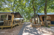 Safari-telte med sanitære faciliteter på Camping Aminess Maravea i Kroatien, omgivet af træer og stier.