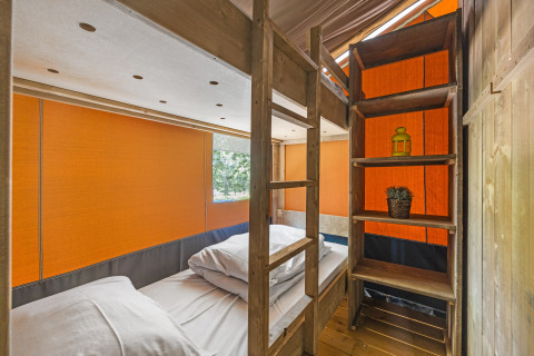 Interieur van een safaritent met stapelbed en houten rekken bij Camping Aminess Maravea in Kroatië.
