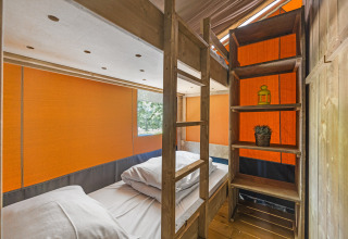 Vista interior de tienda safari con literas y estanterías de madera en Camping Aminess Maravea, Croacia.