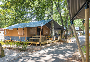 Tienda safari con instalaciones sanitarias y terraza en Camping Aminess Maravea, Croacia, rodeada de árboles.