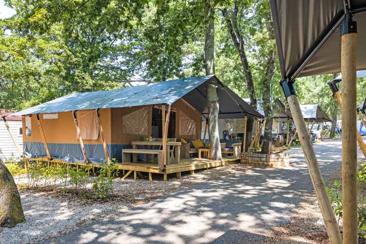 Tienda safari con instalaciones sanitarias y terraza en Camping Aminess Maravea, Croacia, rodeada de árboles.