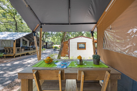 Safari tent met privé sanitair op Camping Aminess Maravea in Kroatië, houten buitentafel en stoelen.