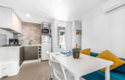 Moderne stacaravan-keuken en eethoek met witte tafel en blauwe bank in Camping Bijela Uvala, Kroatië.