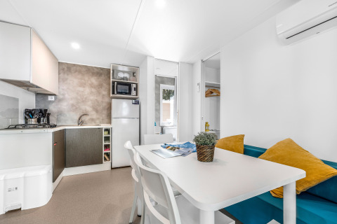 Cucina e zona pranzo moderna in casa mobile con divano e tavolo al Camping Bijela Uvala, Croazia.