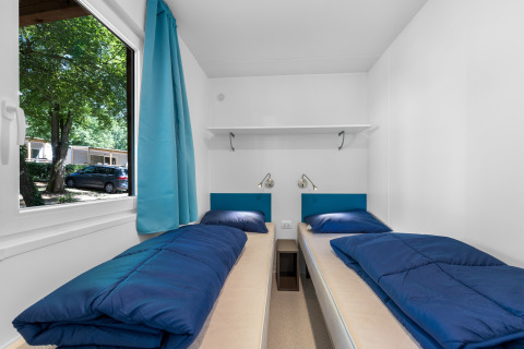 Due letti singoli con biancheria blu in una stanza luminosa del Mobile home Funtana, Camping Bijela Uvala.