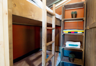 Interno di tenda safari al Camping Polari in Croazia con letti a castello, scaffali e pavimento in legno.