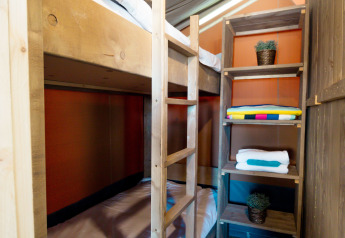 Interno di tenda safari al Camping Polari in Croazia con letti a castello, scaffali e pavimento in legno.