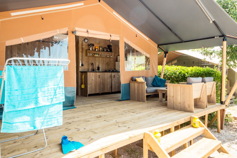 Tienda safari con porche, asientos, cocina y tendedero en Camping Polari, Croacia, día soleado.
