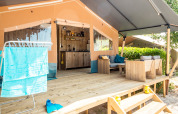 Tienda safari con porche, asientos, cocina y tendedero en Camping Polari, Croacia, día soleado.