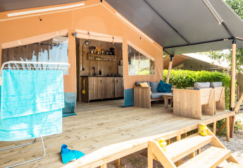 Tenda safari con veranda, salotto, cucina e stendino al Camping Polari in Croazia in una giornata soleggiata.