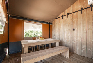 Vista interior de una tienda safari con bancos de madera y aire acondicionado en Camping Polari, Croacia.