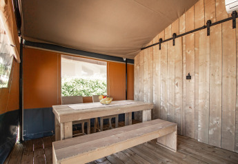 Interior view of a safari tent with wooden benches, table, and air conditioning at Camping Polari, Croatia.