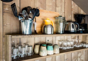 Mensola da cucina in tenda safari con utensili, bollitore, macchina da caffè e tazze al Camping Polari, Croazia.