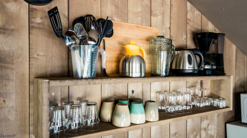 Mensola da cucina in tenda safari con utensili, bollitore, macchina da caffè e tazze al Camping Polari, Croazia.