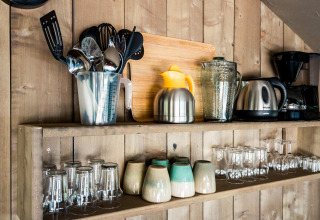 Kitchen shelf in safari tent with utensils, kettle, coffee maker, mugs and glasses at Camping Polari, Croatia.