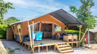 Safari tent met eigen sanitair en airconditioning, houten veranda, zithoek en buitenmeubilair.