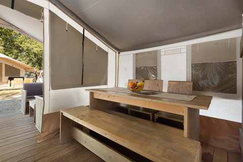Vista interior de una Safari Tent Luxury en Camping Polari, Croacia, con mesa y bancos de madera.