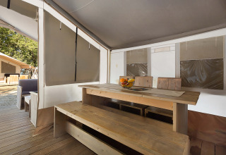 Vista interna di una Safari Tent Luxury al Camping Polari in Croazia con tavolo e panche in legno.