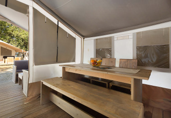 Vista interior de una Safari Tent Luxury en Camping Polari, Croacia, con mesa y bancos de madera.