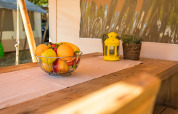 Fruitschaal op een houten tafel in een luxe safaritent, met een gele lantaarn en bloempotten.