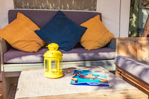 Angolo relax nella Safari Tent Luxury al Camping Polari, Croazia, con cuscini colorati e lanterna gialla.