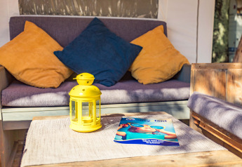 Angolo relax nella Safari Tent Luxury al Camping Polari, Croazia, con cuscini colorati e lanterna gialla.