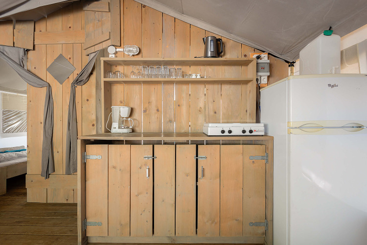 Kitchen area inside Safari Tent Luxury at Camping Krk in Croatia, featuring wooden cabinets and fridge.
