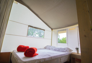 Vista interna della Safari Tent Luxury con letto matrimoniale e asciugamani rossi al Camping Krk, Croazia.