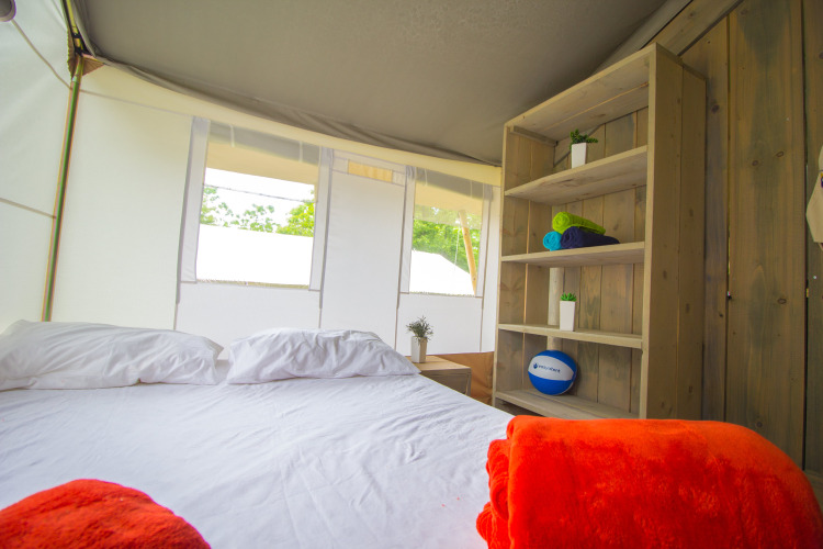 Interieur van luxe safaristent met bed, kussens en plank bij Camping Krk in Kroatië.