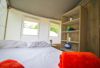 Interieur van luxe safaristent met bed, kussens en plank bij Camping Krk in Kroatië.
