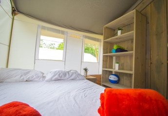 Interior of a luxury safari tent with bed, pillows, and shelf at Camping Krk in Croatia.