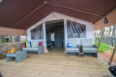 Safari Tent Luxury al Camping Krk in Croazia con ampia terrazza, posti a sedere e cuscini colorati.