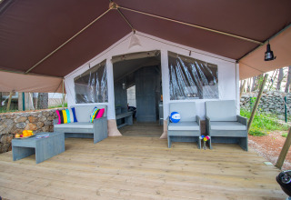 Safari Tent Luxury al Camping Krk in Croazia con ampia terrazza, posti a sedere e cuscini colorati.