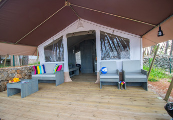 Safari Tent Luxury al Camping Krk in Croazia con ampia terrazza, posti a sedere e cuscini colorati.