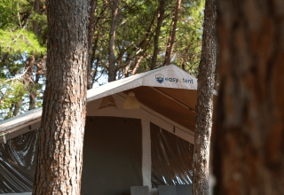 Safari Tent Luxury al Camping Krk in Croazia, circondata da alti alberi, vista dall'esterno di giorno.