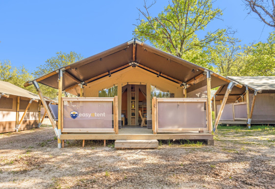 Safari tent Cozy, terrasse couverte, entourée d’arbres et panneau 'easytent' visible sur le devant.