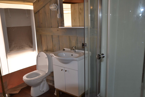 Baño dentro de tienda safari con inodoro, lavabo y ducha en Camping Polari en Croacia.